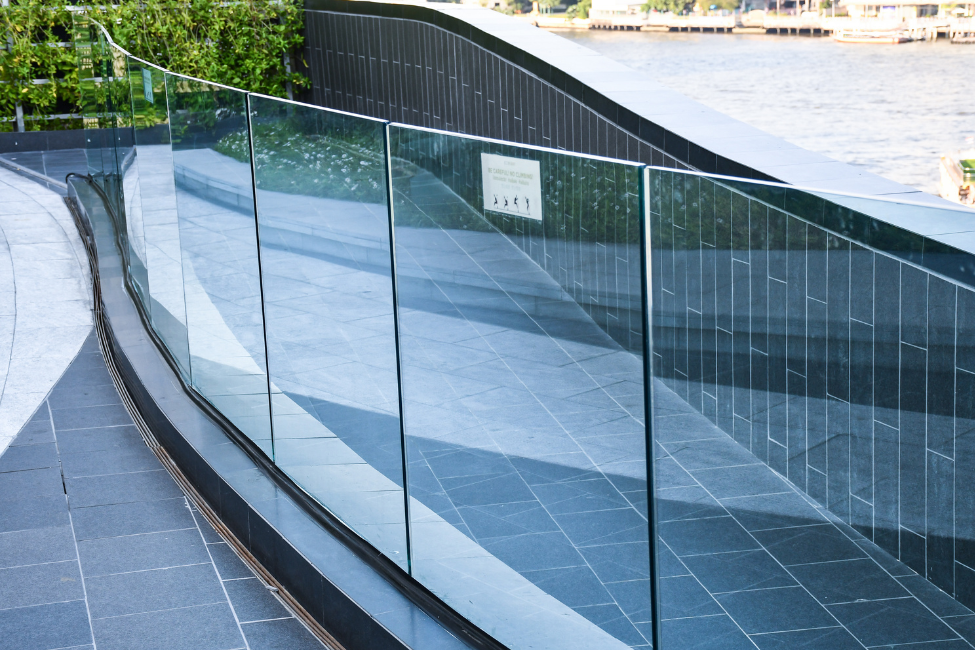 A frameless glass balustrade along a walkway outside a building